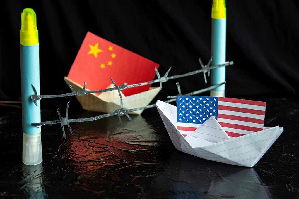 China and USA flags in paper boats with barbed wire
