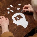 Elderly person completing head-shaped jigsaw puzzle
