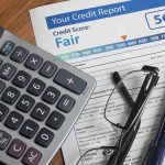 Calculator and glasses on credit report document