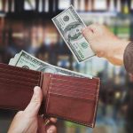 A hand withdrawing cash from a wallet in a blurred background
