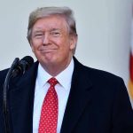 Man in suit and tie speaking at podium