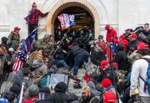 Pardoned Rioter’s Plot: Jeffries Assassination Shocker Crowd storming a building entrance with flags and signs