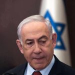 Man in suit with Israeli flag in background