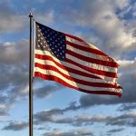 American flag waving against cloudy sky