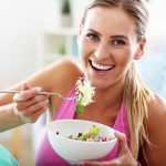 Woman smiling and eating a salad bowl