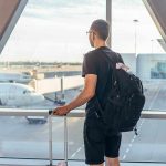 A traveler looking out of an airport window at parked airplanes