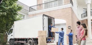 Workers unloading boxes from a moving truck in a residential driveway