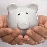 Hands holding a white ceramic piggy bank