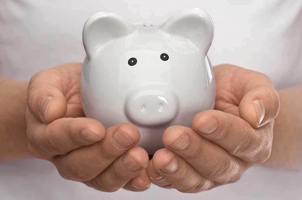 Hands holding a white ceramic piggy bank