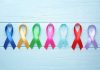Colorful awareness ribbons on light wooden background.