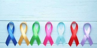 Colorful awareness ribbons on light wooden background.