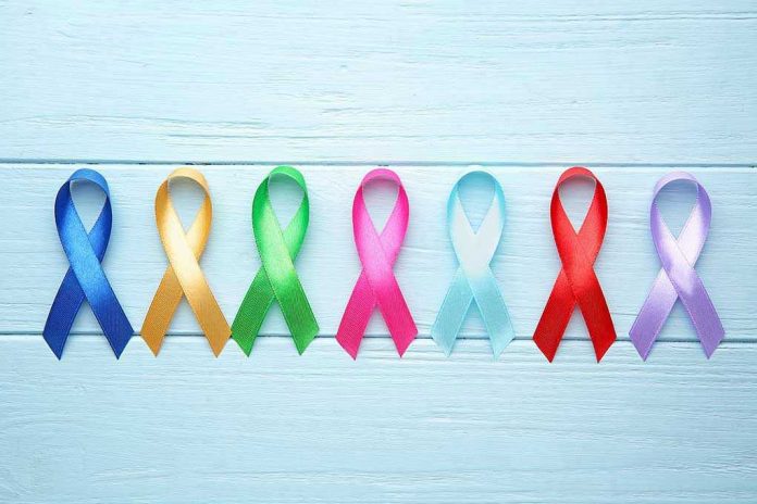 Colorful awareness ribbons on light wooden background.