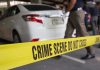 Crime scene tape blocking off white sedan