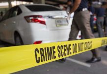 Crime scene tape blocking off white sedan