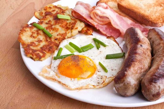 shutterstock_28053688.jpg A hearty breakfast plate featuring a fried egg, crispy bacon, sausages, hash browns, and toasted bread garnished with green onions