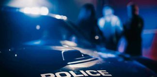 Police car with blurred figures in the background.