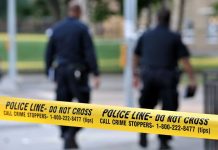 Killer Loose After Brown Massacre Police officers walking past caution tape at a crime scene