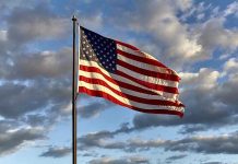 American flag waving against cloudy sky.