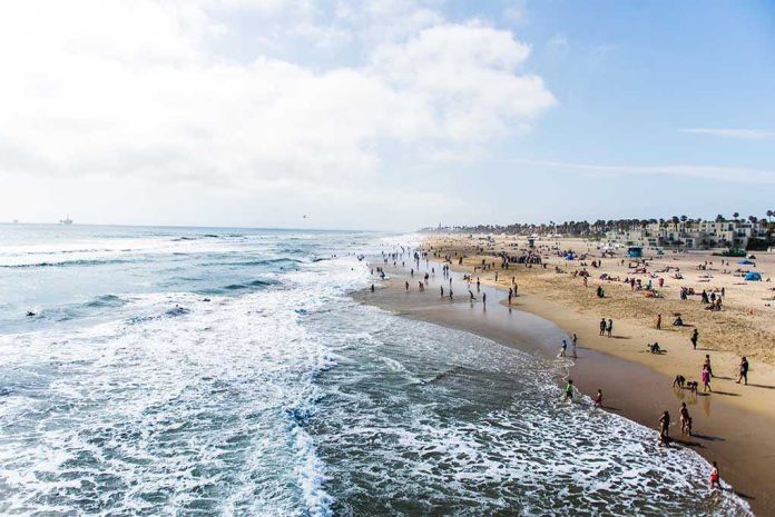 Crowded beach with waves and people enjoying sun.