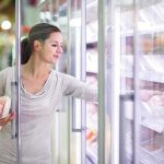 A woman shopping in the frozen food aisle of a supermarket