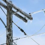 Icy power lines and a utility pole against a blue sky