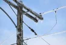 Icy power lines and a utility pole against a blue sky