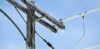 Icy power lines and a utility pole against a blue sky