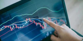 US Stocks Explode After Surprise Truce News Hand pointing at stock market graph on laptop.