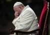 Pope sitting with his head bowed and hand covering his face