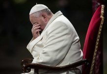 American Pope Defies Trump: Faith vs. Politics Pope sitting with his head bowed and hand covering his face