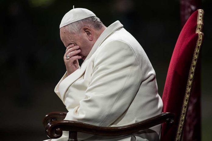 Pope sitting with his head bowed and hand covering his face
