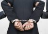 Surgeon Forces Abortion Pills on Girlfriend A person in a suit with hands cuffed behind their back