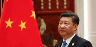A political leader standing beside the Chinese national flag