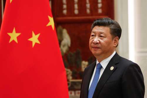 A political leader standing beside the Chinese national flag