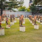 A memorial site with numerous sculptures and flowers in a grassy area