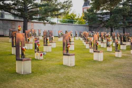 A memorial site with numerous sculptures and flowers in a grassy area