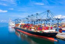 Two Tankers Blink—Prices Jump Container ship docked at a busy industrial port.