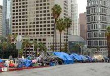 Row of tents along a city street with skyscrapers in the background