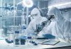 Scientists in protective suits using a microscope in a laboratory