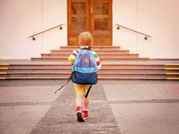shutterstock_1146209870 child with backpack walking toward school steps