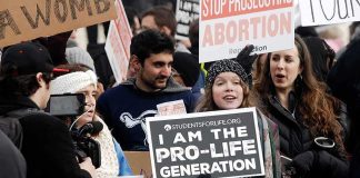 Power Shift: Doctor Overrules Boards Group of protesters holding pro-life signs at a rally