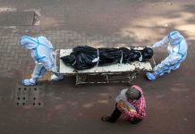 Flood Horror: Names Lost, DNA Filed health workers in PPE move a body on a stretcher