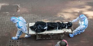 health workers in PPE move a body on a stretcher
