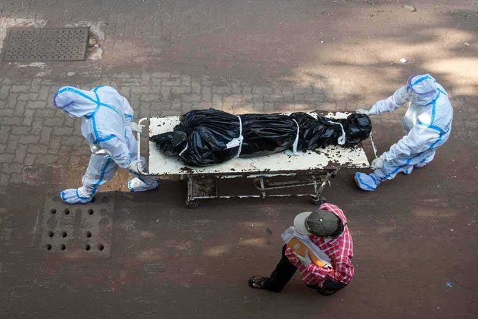 shutterstock_1745538830 health workers in PPE move a body on a stretcher