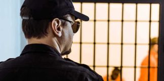 Security guard watching inmates behind jail bars
