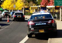 Police cars with flashing lights near school buses on a city street