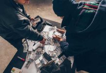Triple-Digit Shock – The Iran Stat They Hide Two people sorting stacks of U.S. dollar bills on a table