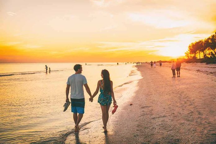 shutterstock_1325105396 couple walking on a beach at sunset