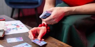 A Rare Card Collection Attracted Real Violence Person laying tarot cards on a wooden table