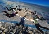 Skydivers forming a circle in freefall over a city and farmland